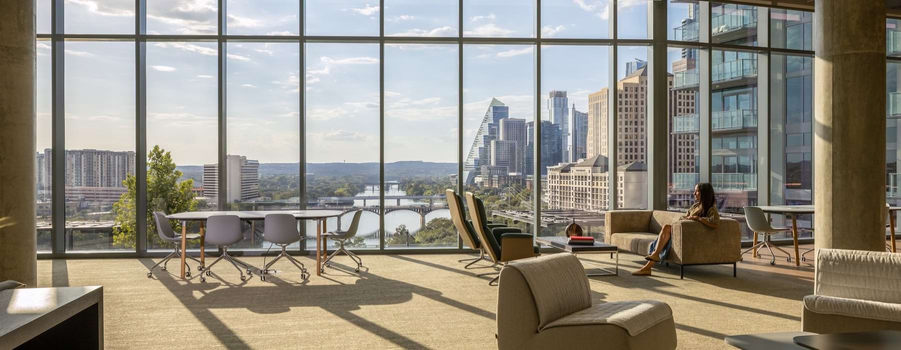a room with large floor-ceiling windows and seating options